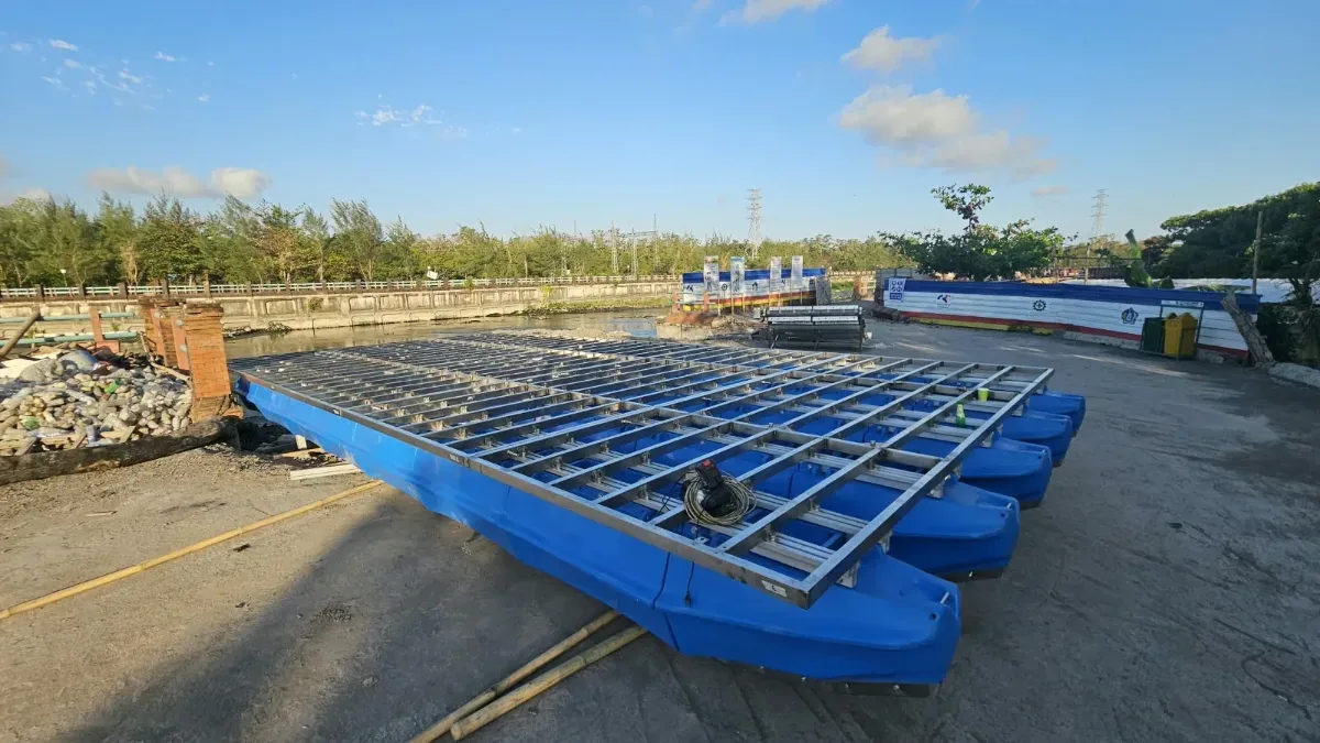 Platform ponton biru dengan rangka grid di area terbuka dekat perairan sebelum dipasangi dek