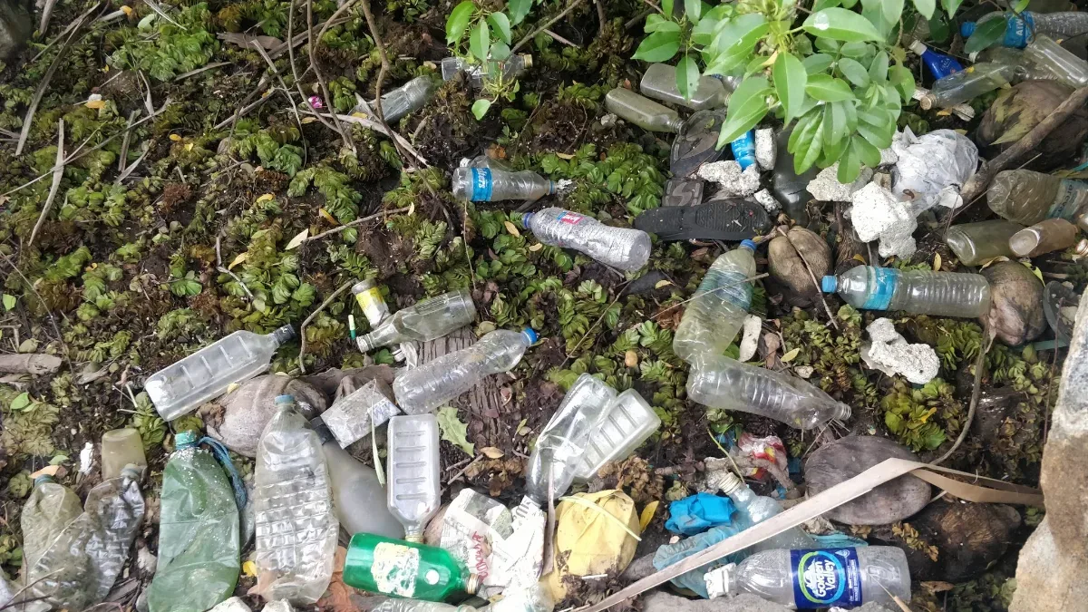 Botol plastik dan sampah menumpuk di tepi sungai
